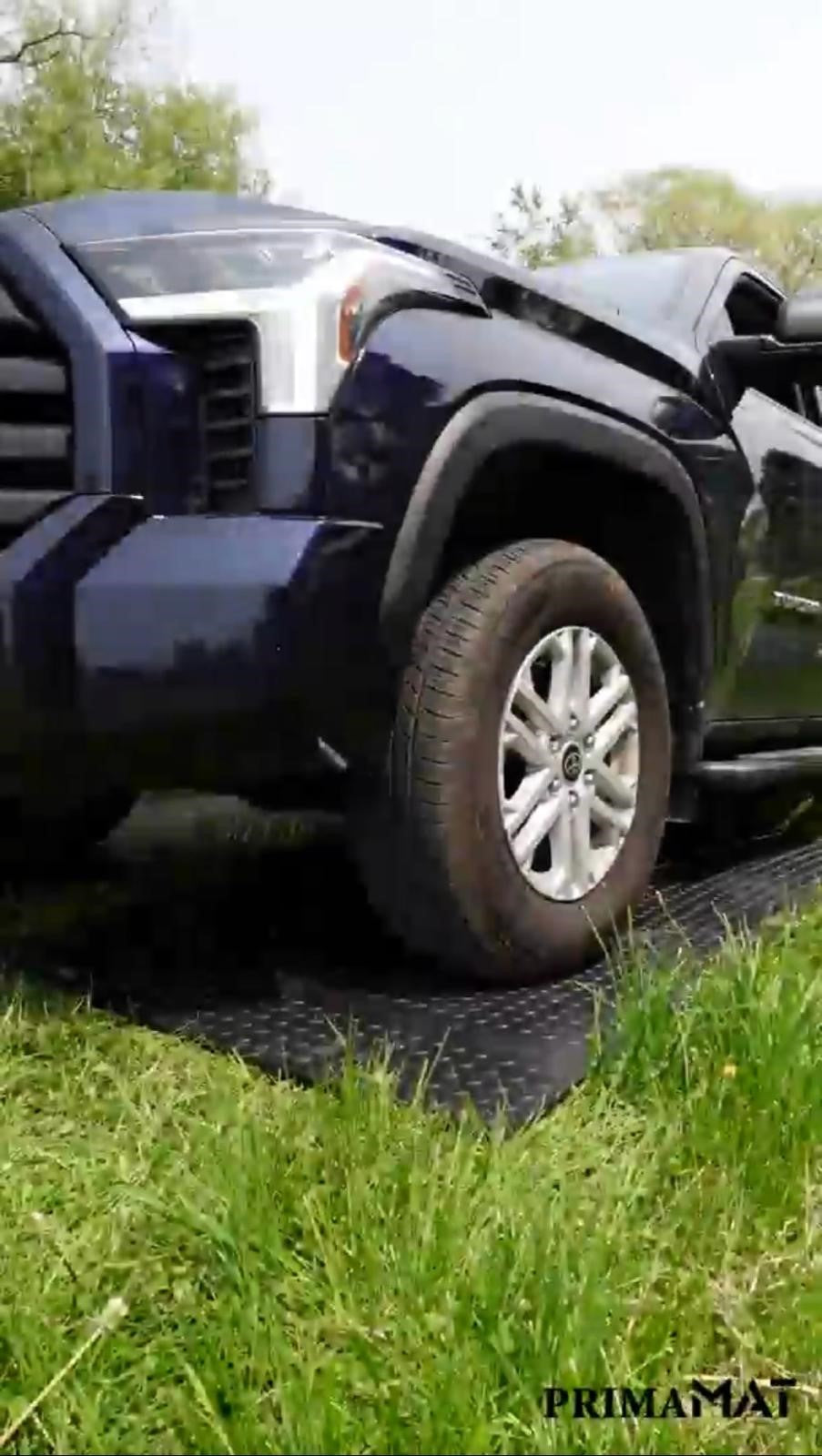 Car parked on grass protected by PrimaMat mats.