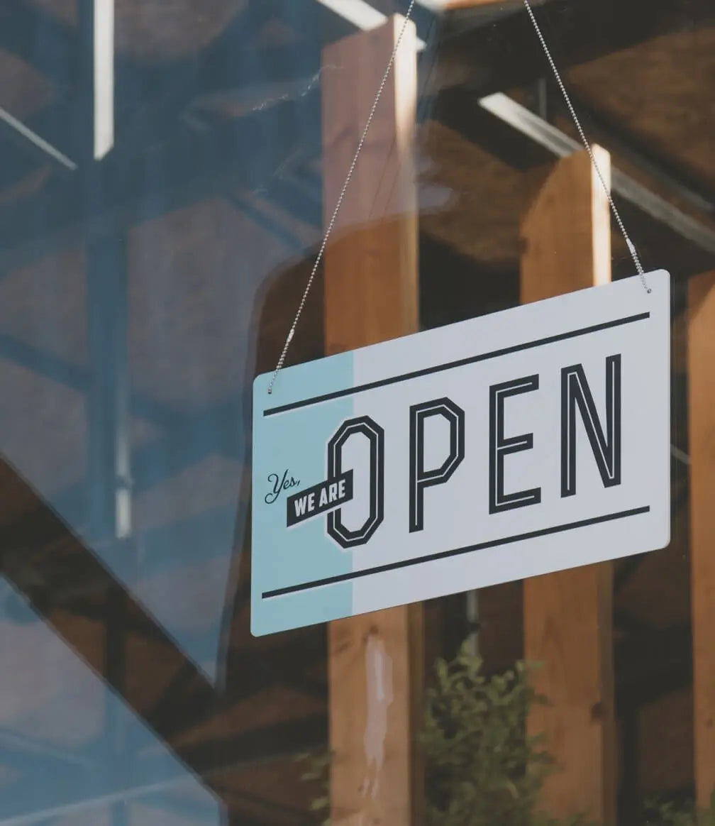 Hanging sign on a glass door that reads 'Yes, We Are Open.'